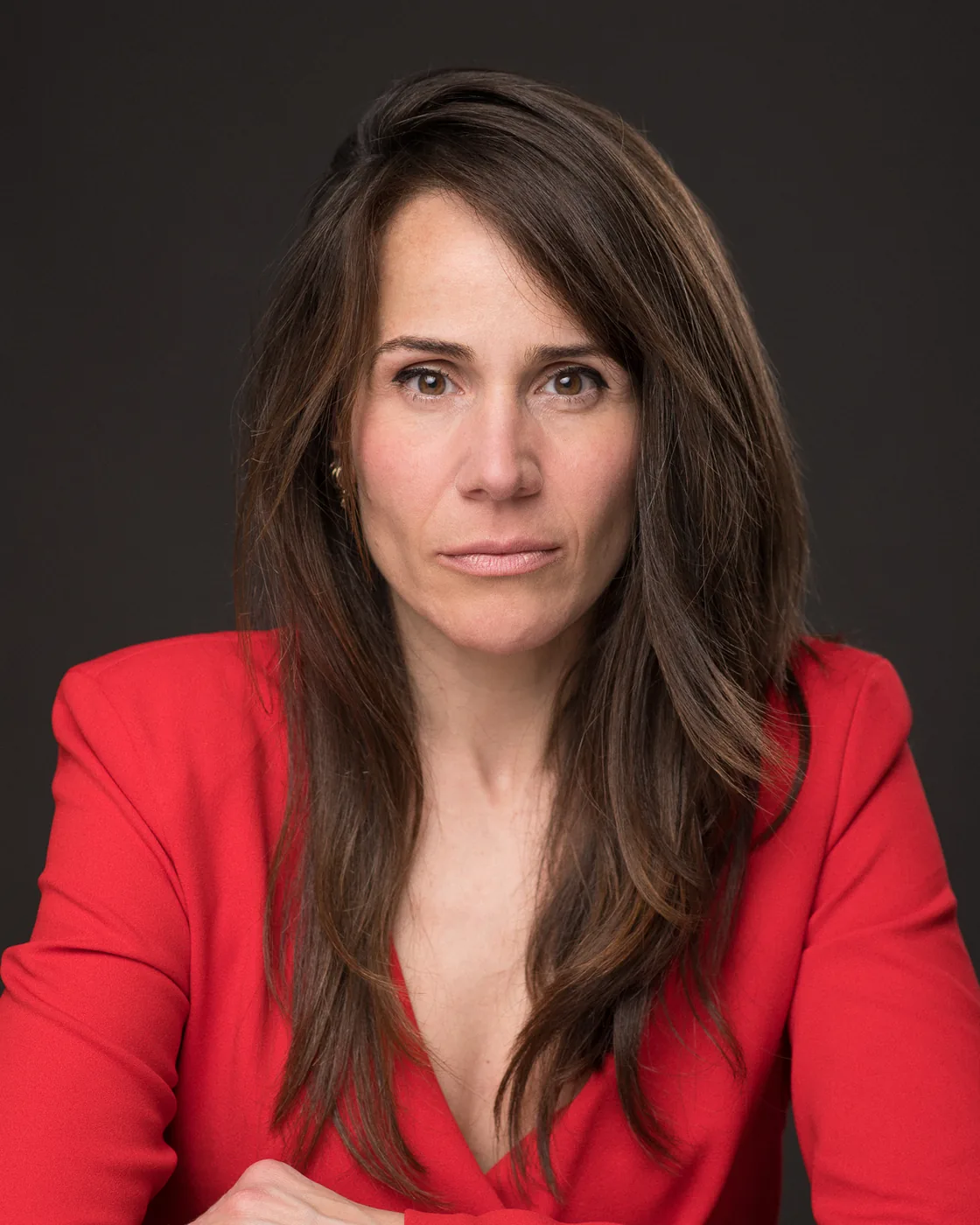 Miriam Martín con blazer rojo, retrato frontal sobre fondo oscuro
