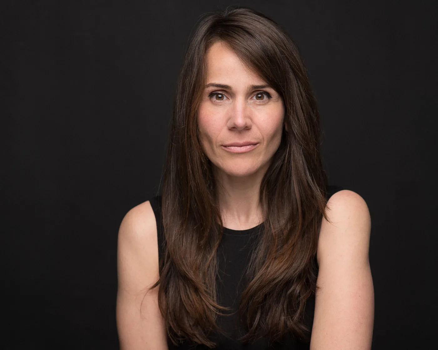 Miriam Martín con top negro sobre fondo negro, retrato dramático